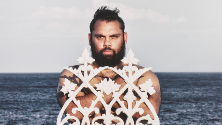 A man posing in front of an ironwork art piece