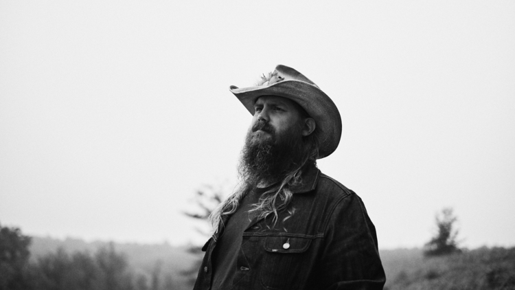 Chris Stapleton looks into the distance wearing a cowboy hat.