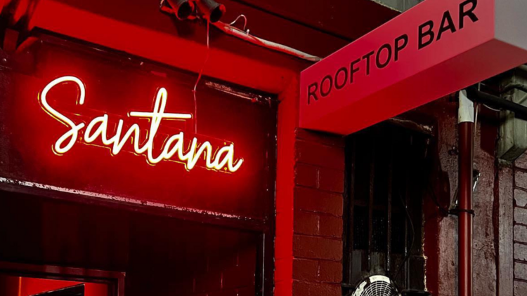 Red neon sign at rooftop bar entrance.