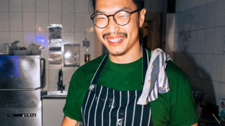 Chef Steve Chan smiling for the camera in a striped apron. 