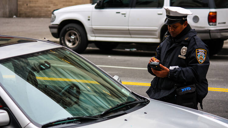 an NYPD police officer giving out a ticket to a parked car