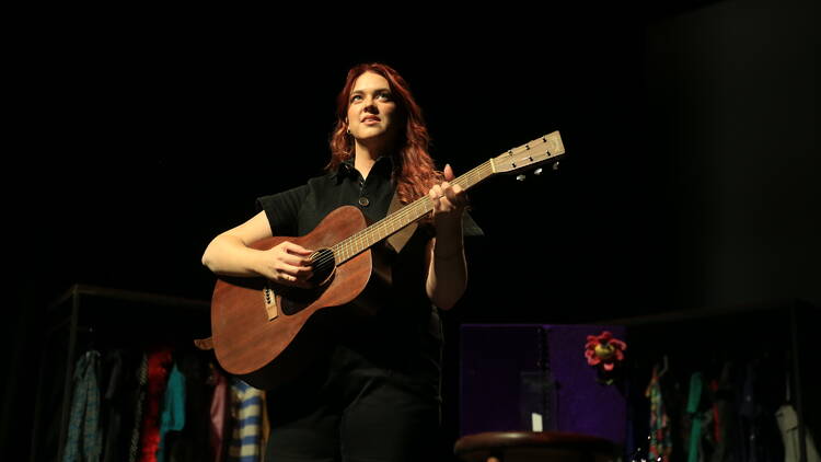 A woman on stage with a guitar