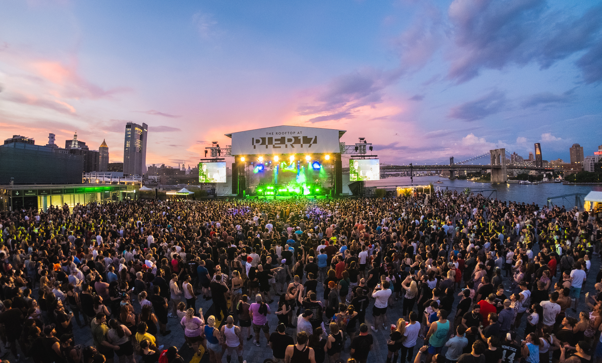 A crowd watches a show at Pier 17 at sunset.