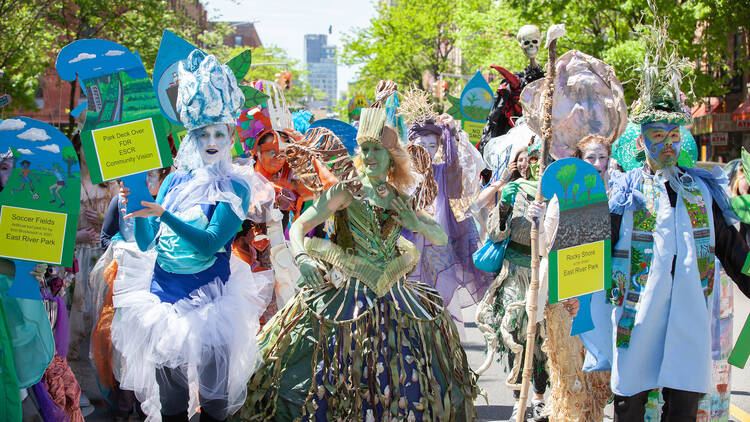 People dressed in elaborate costumes walk in an eco parade. 