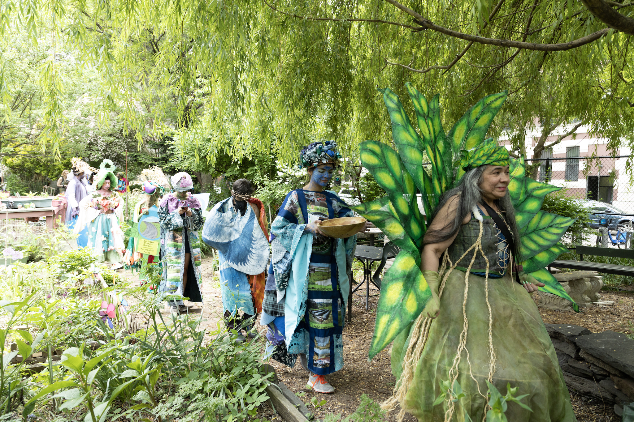 People in costumes walk through a community garden.