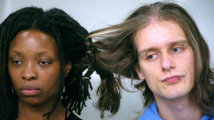 A black person and a white person with their hair woven together