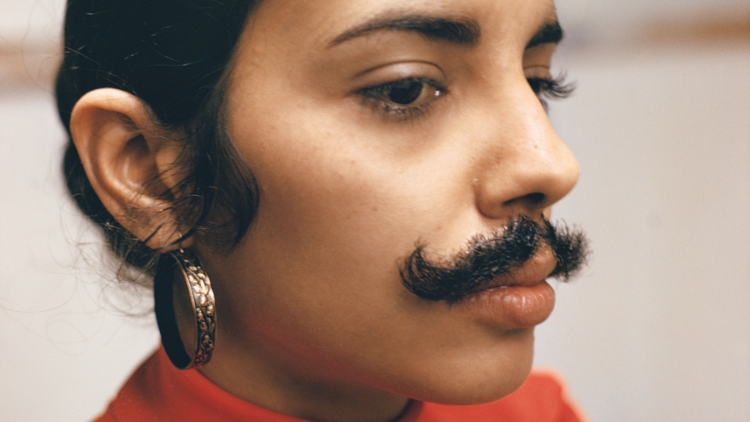 A woman with hair glued on as a moustache
