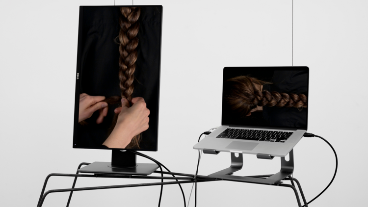 A monitor and a laptop showing images of braided hair