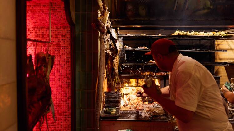 A chef cooking over fire at Good Luck Restaurant Lounge
