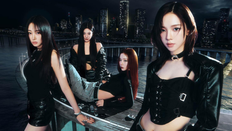The four members of Aespa wear black outfits, posing in a city
