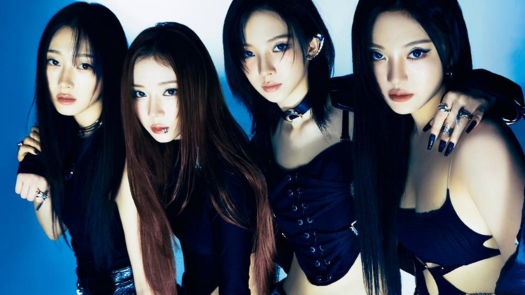 The four members of Aespa wear black outfits, posing with arms around each other