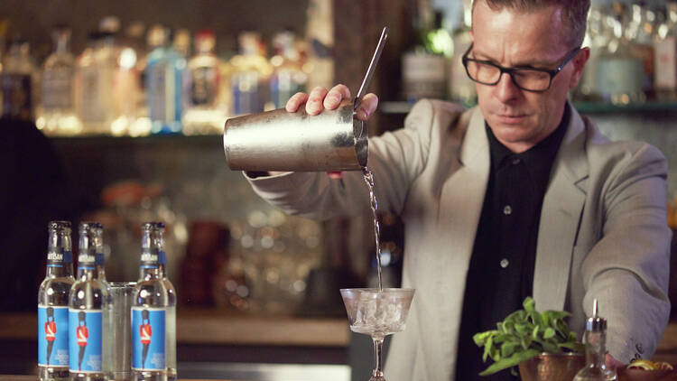 Mixologist pouring a cocktail at a bar