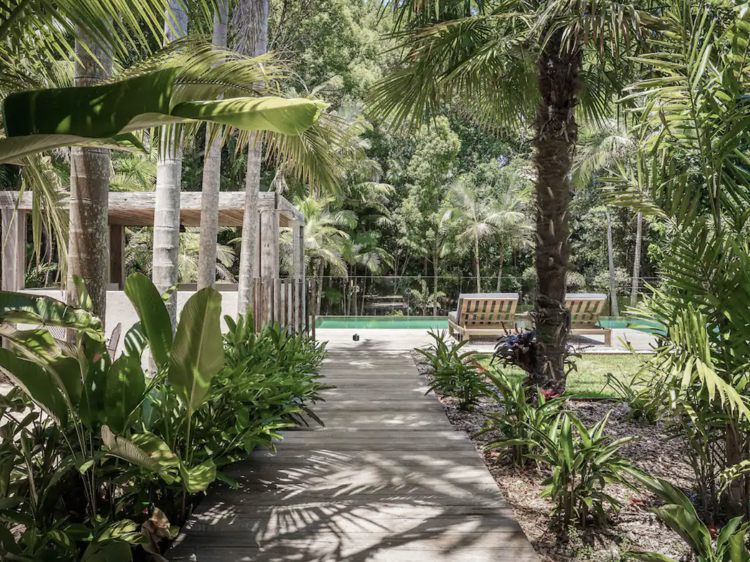 Treelined pathway leading to outdoor pool of Airbnb rental in Clunes, NSW.