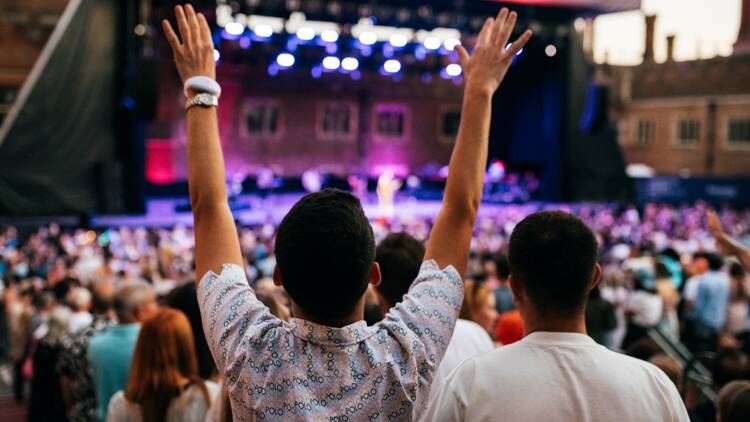 a person dancing with their hands up at a music festival