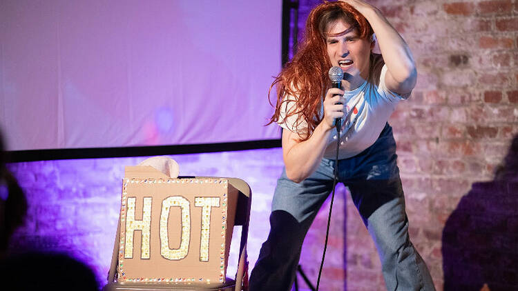 A performer on stage with a box reading "HOT."