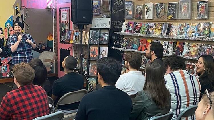 A comedian performs in a comic book store.
