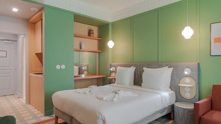 Vintage-inspired apartment with green walls, red armchair and a bed.