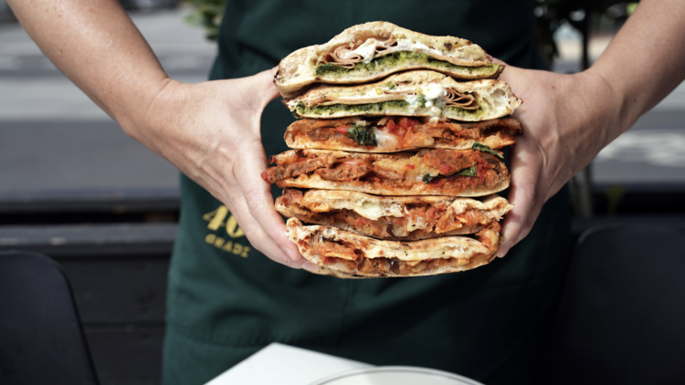 Chef holding a stack of 400 Gradi's panuozzo sandwiches.