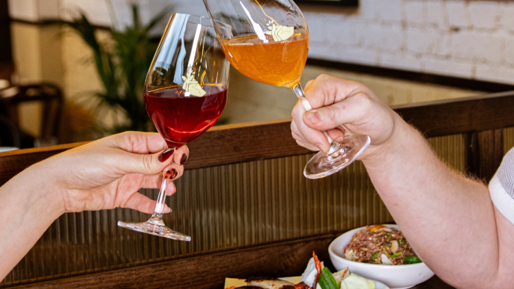 Guest clinking glasses of wine at a table of assorted dishes at Bar Spontana.