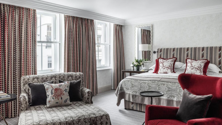 Suite at Brown's Hotel furnished with a large bed, large windows and two armchairs.