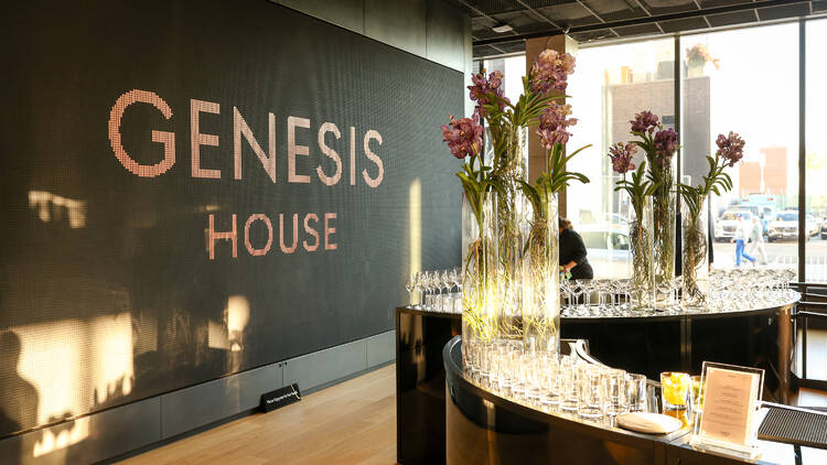 A Genesis House sign with flowers.