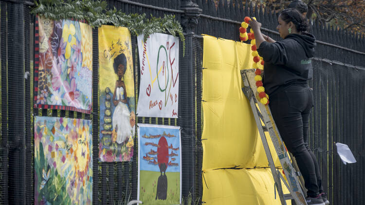 A woman hangs up artwork as part of the COVID memorial.