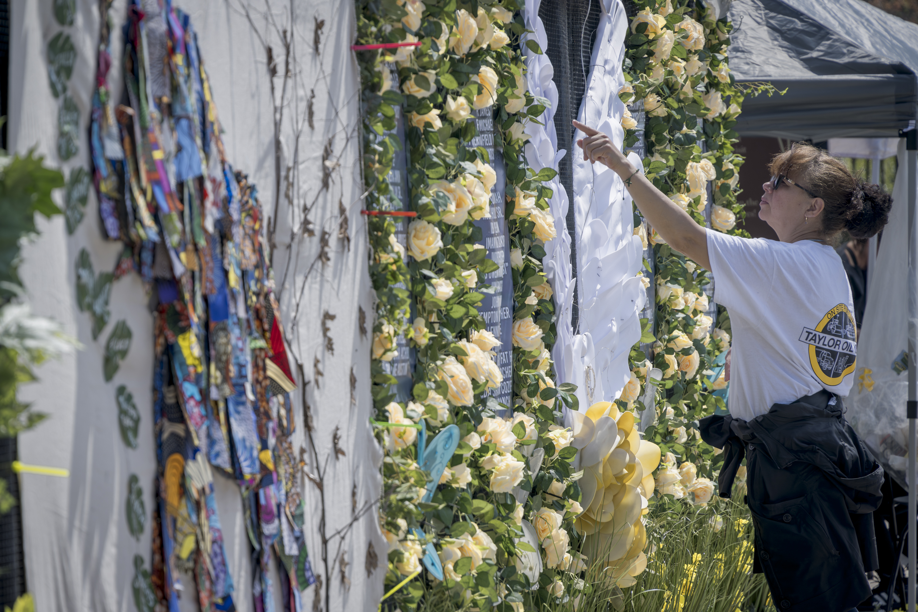 A woman hangs up artwork as part of a COVID memorial.