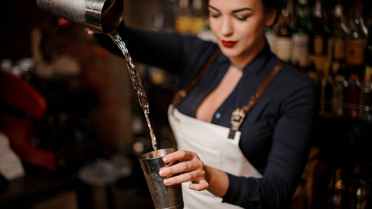 Bartender pouring a cocktail from a tumbler