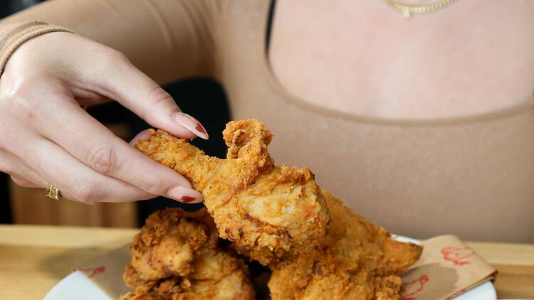 A person holding a piece of fried chicken