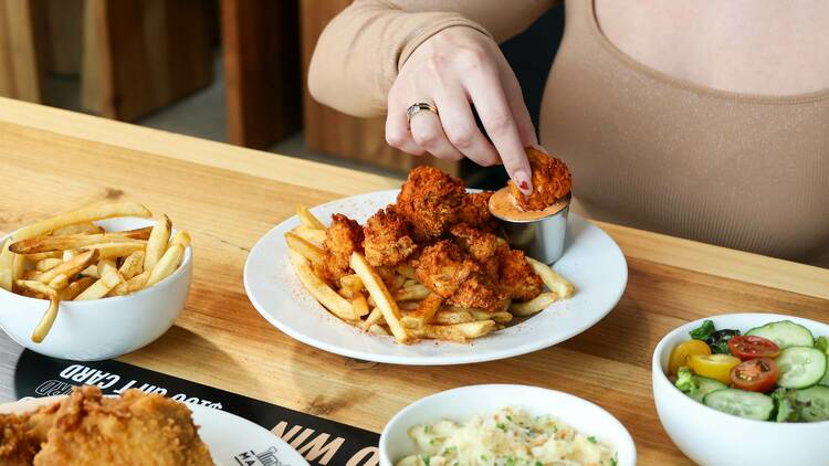 A person dipping a chicken nugget in sauce