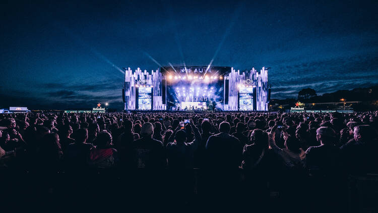 a nighttime shot of a festival crowd looking at the main stage