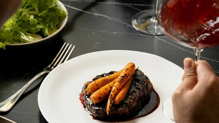 A plate of steak topped with carrots 