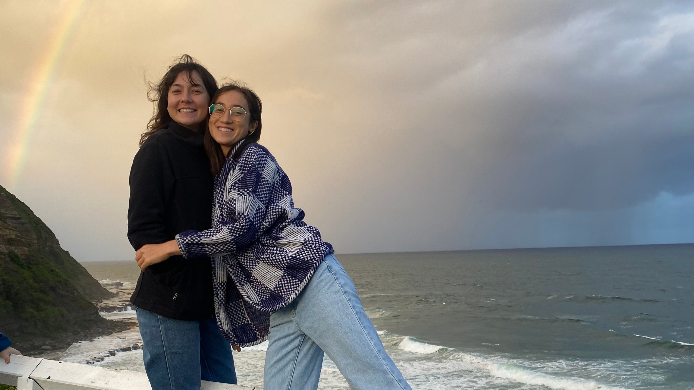 Two girls smiling with rainbow in background