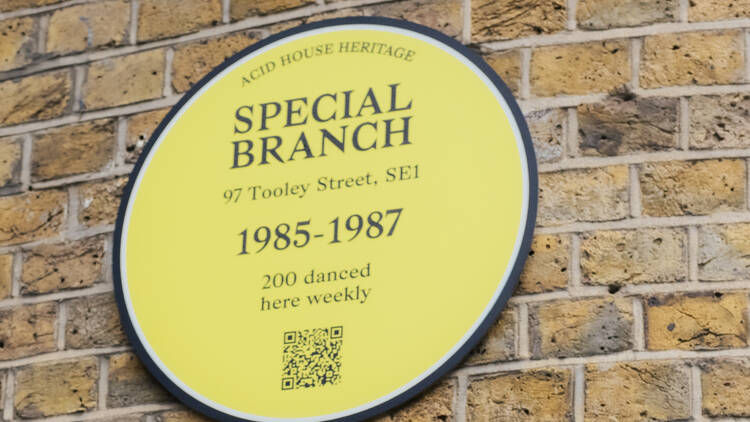 A yellow plaque on a brick wall