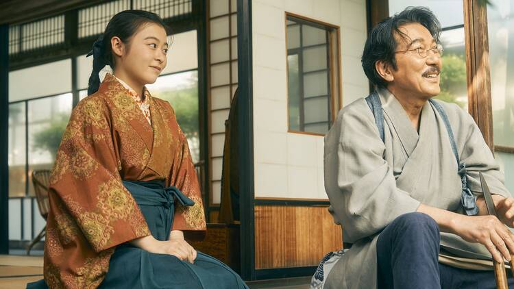 A young Japanese woman sits with an older man laughing