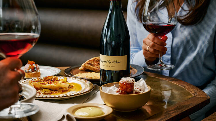 Plates of food and people drinking wine at Wally's.