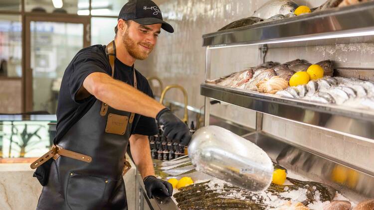 Fishmonger scooping ice on fresh fish