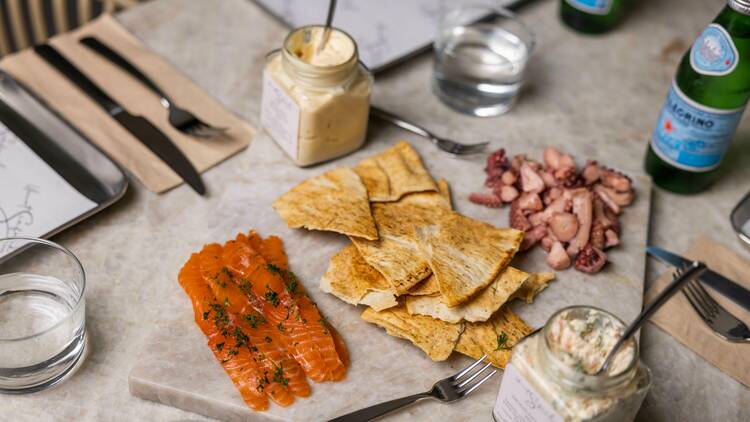 Platter of salmon, crackers, pickled octopus and dips