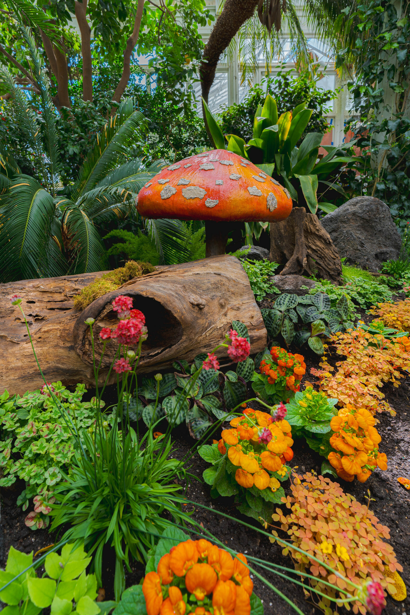 Colorful orange flowers with a mushroom sculpture.