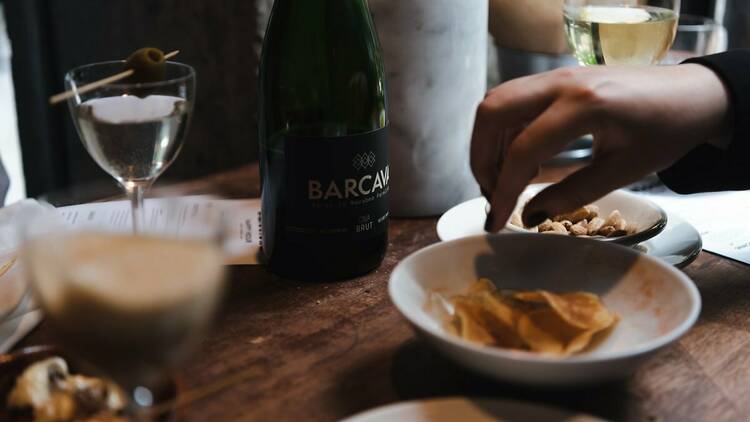 A hand hungrily reaches for bar snacks during happy hour at Barcelona Wine Bar