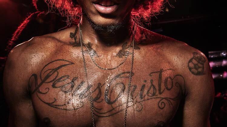 Foto de um torso suado com uma tatuagem escrito Jesus Cristo