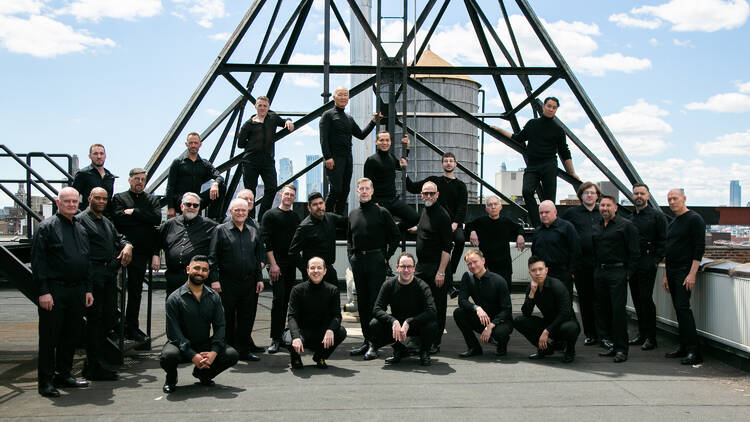 men in black turtle necks pose on a rooftop