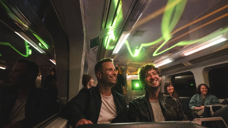 People sitting on a train lit with cool green lights.