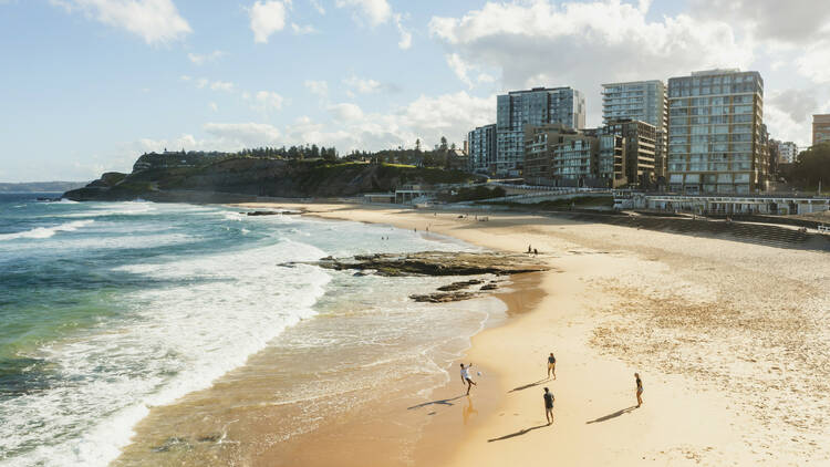 Aerial view of young people playing a ball game along the water at Newcastle Beach