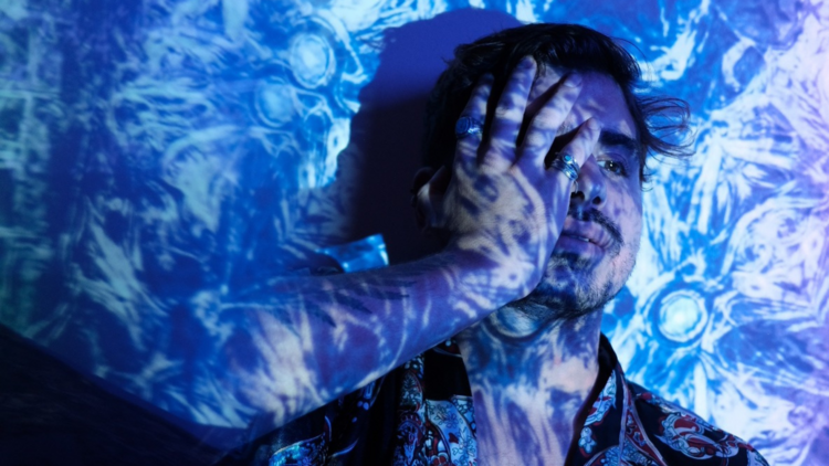 A person with blue patterns projected over them and a hand on their face