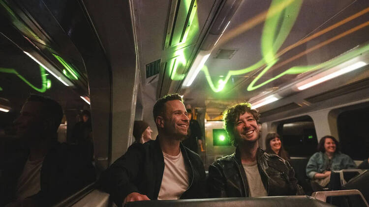 People sitting on a train lit with cool green lights