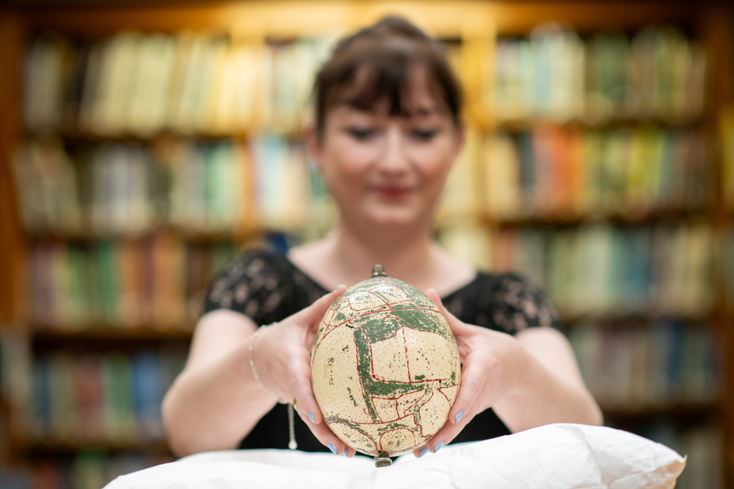ZSL archivist Natasha Wakely  holds a 1930s ostrich egg,  decorated with a map of  Whipsnade Zoo and once owned  by the first Whipsnade Zoo  superintendent, Captain W P. Beal.