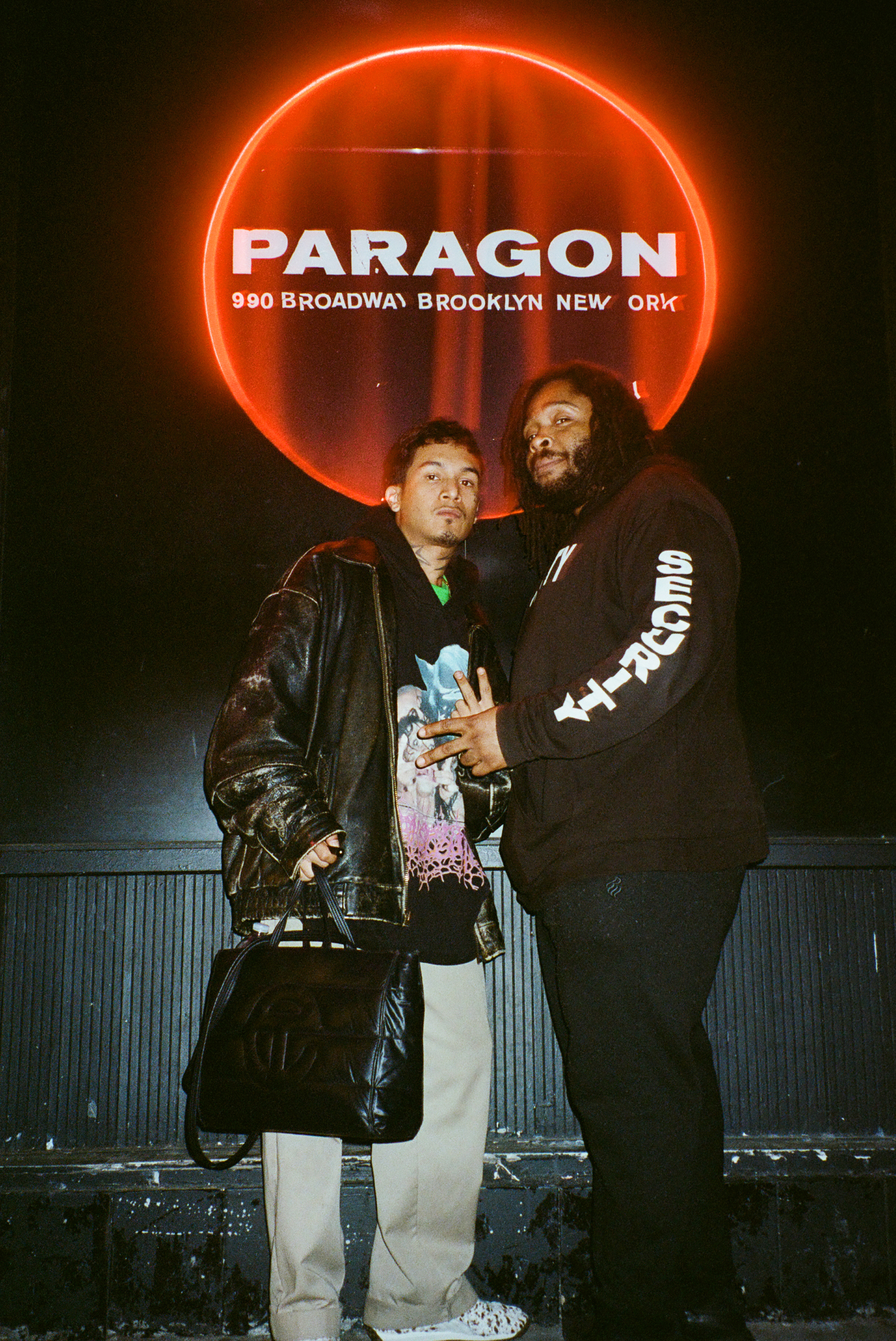 two people pose outside a nightclub 