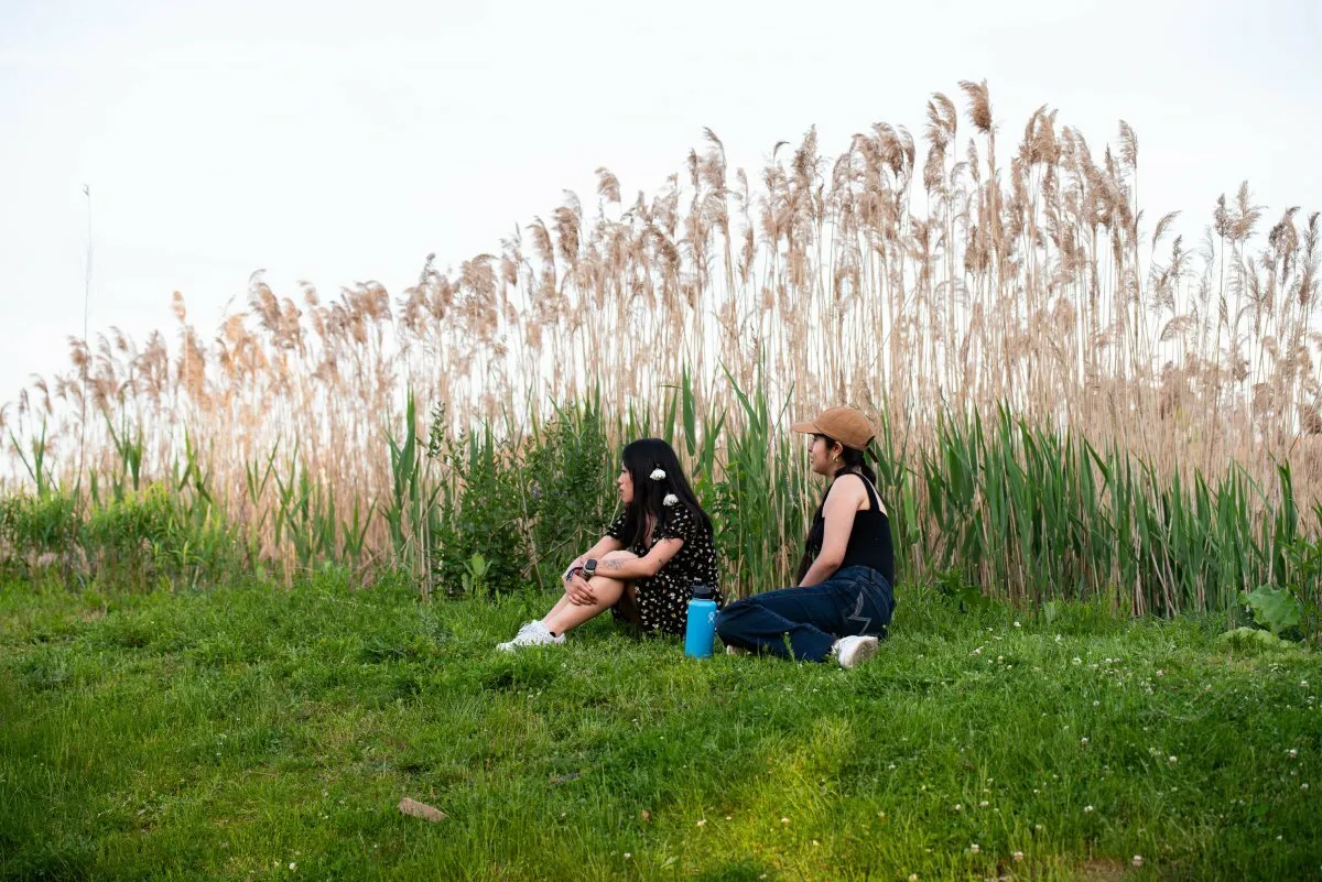 Two fans sit near wild grass at Boston Calling on Saturday, May 25, 2024.