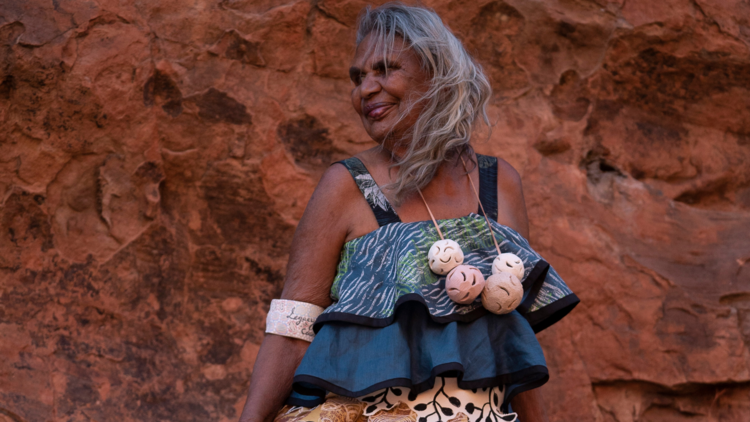 A woman wearing a ruffled dress in front of a red rock face